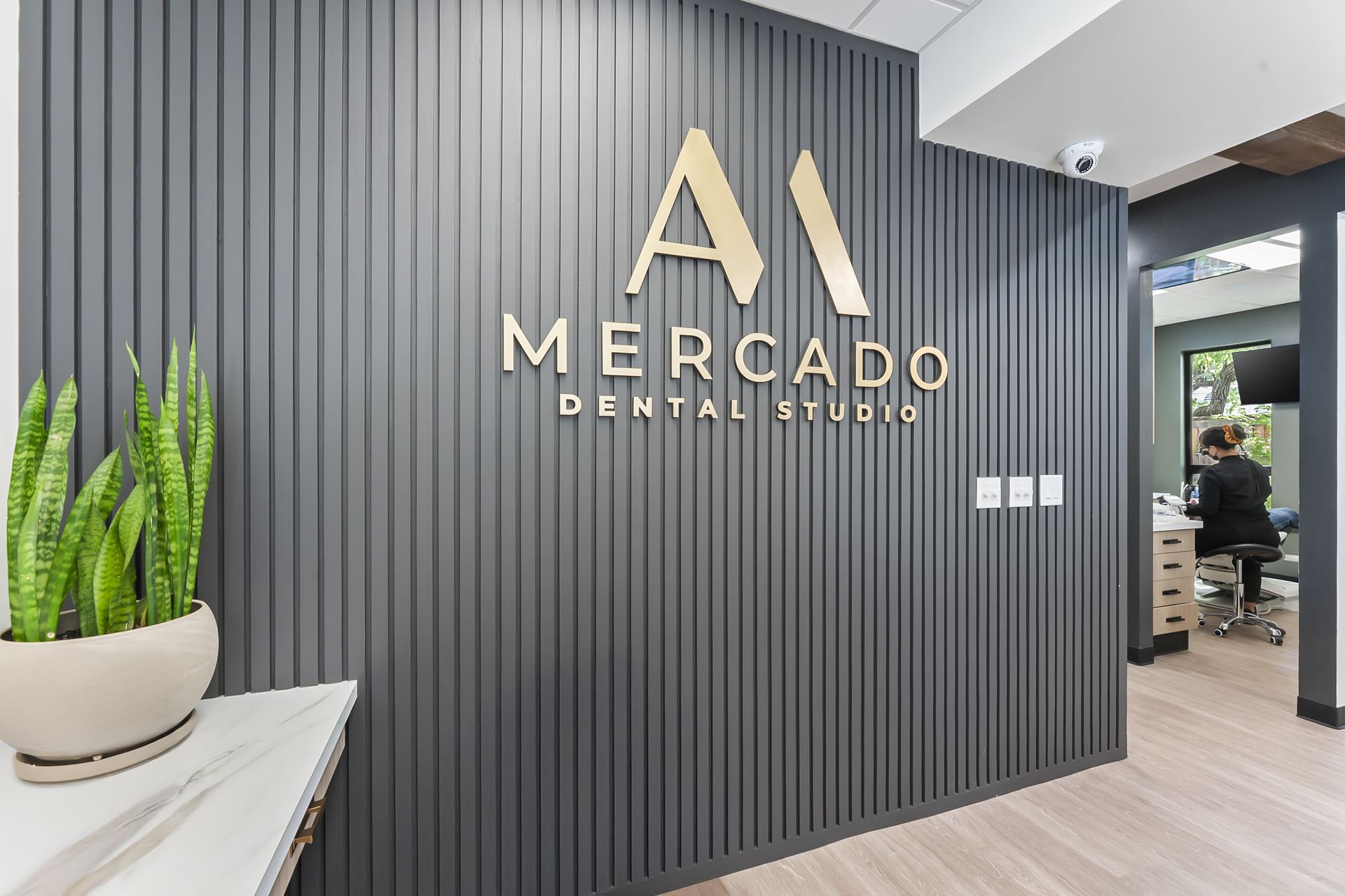 Gold M logo on charcoal slatted panel wall